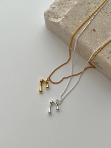 Detailed close-up of liquid metal teardrop pendants in gold and silver on stone