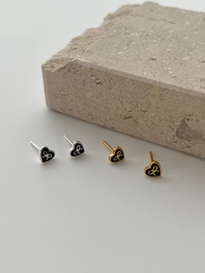 Detail of heart-shaped earrings with black enamel and a bow motif in gold and silver
