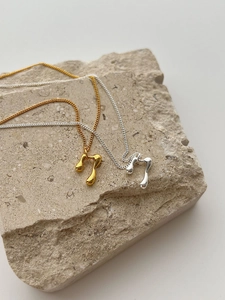 Detailed view of fluid lava pendants in gold and silver finish on textured stone