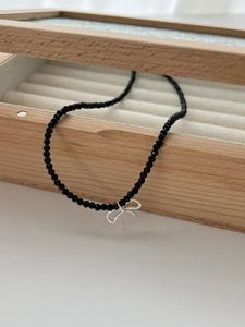 Détail du pendentif nœud en argent S925 sur collier en perles d'onyx noires avec boîte