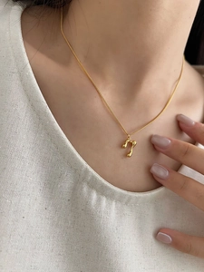 Macro shot of 18K gold-plated necklace with fluid lava-textured number 7 pendant