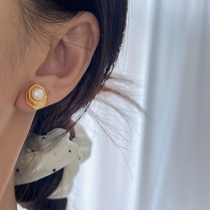 Élégantes boucles d'oreilles perles hexagonales dorées avec motif lotus sur le mannequin