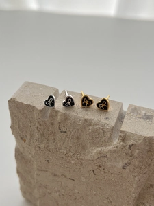 Detail of heart-shaped black enamel stud earrings with bowknot pattern on stone base