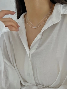 Close-up of a layered 925 silver necklace on a model wearing a white shirt