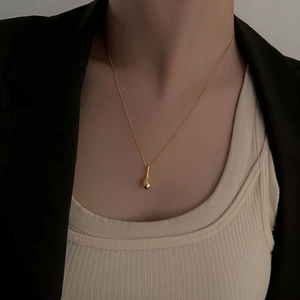 Gros plan d'un collier avec pendentif goutte dorée minimaliste sur un mannequin