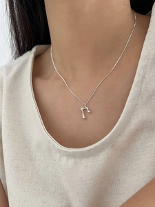 Close-up of minimalist liquid metal pendant and fine silver chain on a model vest