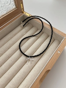 Détail d'un collier en perles noires avec pendentif nœud argenté sur présentoir à bijoux