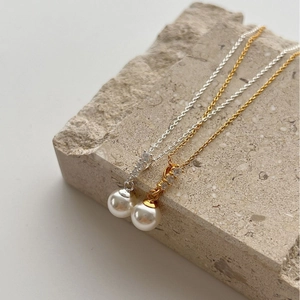 Elegant S925 silver and gold pearl necklaces with zircon accents on a textured stone base