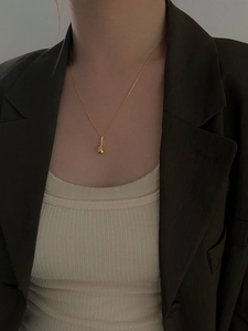 Collier avec pendentif goutte dorée élégante porté par un mannequin en costume chic