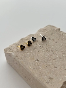 Close-up of 925 sterling silver heart earrings with black enamel and bow detail