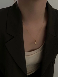Gros plan d'un collier pendentif goutte dorée minimaliste sur le cou d'une femme élégante