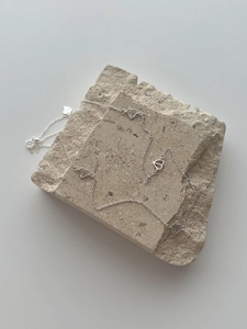 Detail of S925 sterling silver heart necklace with lobster clasp on textured stone