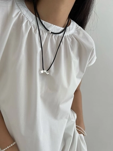 Gros plan d'un collier en onyx noir minimaliste avec chaîne en argent et perles superposées
