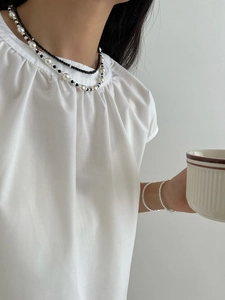 Detail view of S925 sterling silver black spinel beaded necklace layered with white blouse