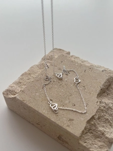 Close-up of minimalist S925 sterling silver chain with hollow heart pendants on a stone