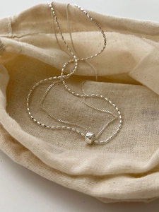 Macro detail of S925 sterling silver chain with a rhombic pattern barrel bead pendant