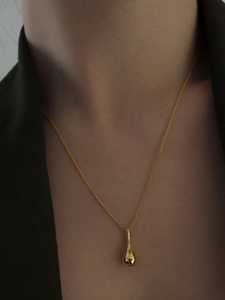 Gros plan d'un collier avec pendentif goutte d'eau dorée minimaliste sur un modèle en costume