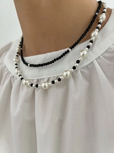 Double-layer necklace featuring black faceted beads and white pearls on a model