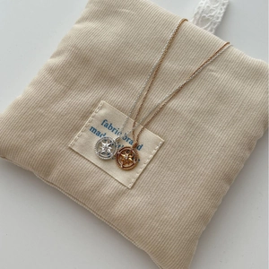 Elegant gold and silver star compass necklaces on soft beige corduroy cushion