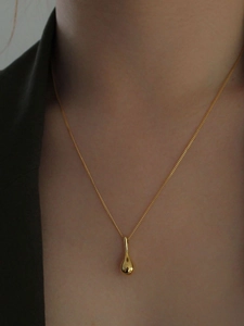 Gros plan d'un collier avec pendentif goutte d'eau dorée sur le cou d'un modèle