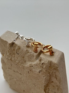 Detailed view of 925 silver bow stud earrings in gold and silver finish on stone