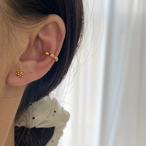 Elegantes Set aus goldener Wellen-Ohrklemme und Perlen-Ohrstecker an einem Model