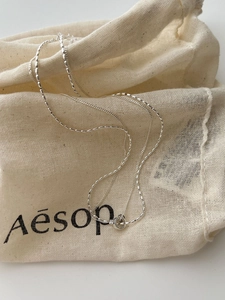 Detailed close-up of double-layered S925 sterling silver beaded chain necklace on fabric