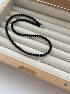 Detail of black onyx bead necklace with polished silver heart pendant in a jewelry box