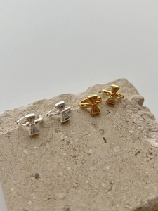 Detail of 925 silver bow stud earrings in gold and silver finish on a natural stone