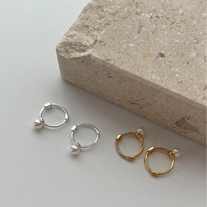 Elegant 925 silver and gold pearl hoop earrings shown on a minimalist stone background