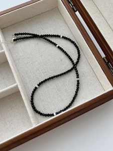Macro detail of black faceted spinel beaded necklace with silver cylindrical spacer beads