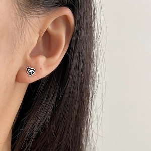 Elegant 925 sterling silver heart earrings with bow design shown on a model earlobe