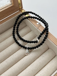 Macro detail of silver heart pendant on black agate bead necklace in velvet box