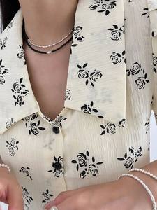 Detail of layered S925 silver necklace with black spinels on floral chiffon shirt