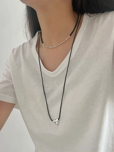 Detail of layered sterling silver heart pendant and black onyx beaded choker necklace