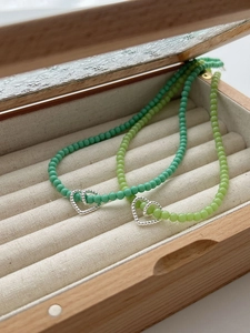 Detail of 925 silver beaded heart necklaces in mint and lime green on linen display