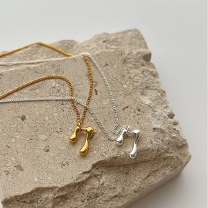 Modern minimalist gold and silver musical note necklaces on natural stone pedestal