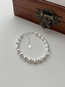 Detail of S925 sterling silver beaded bracelet with matte and polished beads on wood box