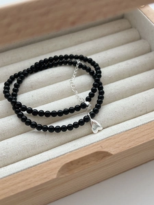 Detail of double-layer black agate beaded bracelet with silver heart pendant in jewelry box