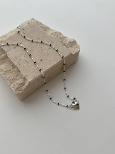 Macro view of S925 silver heart necklace with black beads on a textured stone