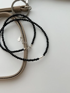 Detailed macro of S925 silver necklace with black faceted beads and irregular pearl accent