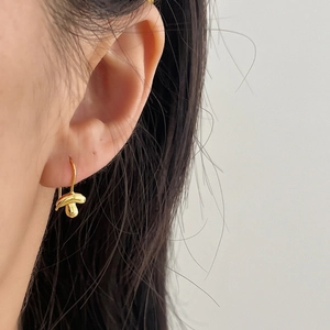 Minimalist gold mushroom dangle earrings with mirror polish finish on model