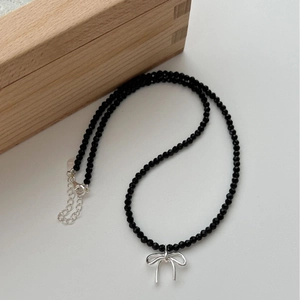 Collier nœud en argent S925 avec perles d'agate noire sur un fond blanc épuré