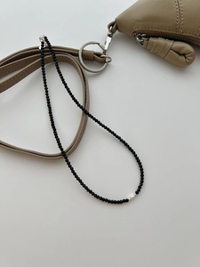 Detailed view of S925 sterling silver black spinel necklace draped over a leather bag strap
