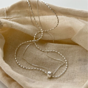Double-layer S925 sterling silver geometric cube pendant necklace on a linen bag