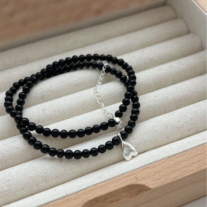 Black agate beaded necklace with silver heart pendant on minimalist velvet jewelry box