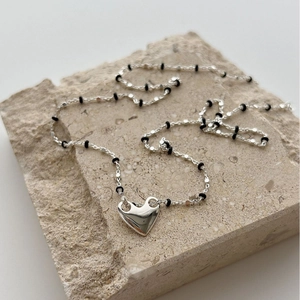 Minimalist S925 sterling silver heart necklace with black beads on a stone background