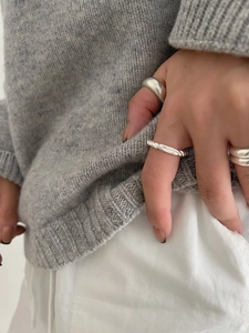 Close-up of minimalist 925 silver braided knot rings worn by a model in a casual style