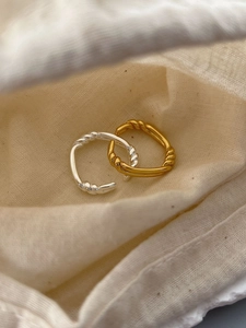Macro shot of silver and gold twisted rope texture rings on a beige linen pouch
