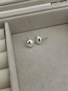 Detailed close-up of textured spherical silver earrings with Midnight Moment engraving